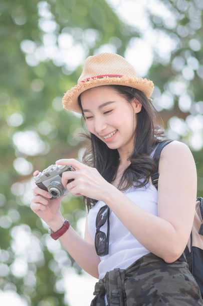 Красива азіатська сольна туристична жінка насолоджується фотографуванням ретро-камери на туристичному місці. Відпустка влітку
.  - Фото, зображення