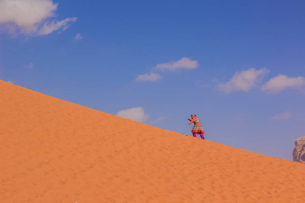 alte muslimische Frau in Wüste Naher Osten arabische Landschaft Umgebung zu Fuß auf einem gelben Sanddünen, östliche Entourage Tapete Muster Bild mit leeren Kopierraum für Text  - Foto, Bild