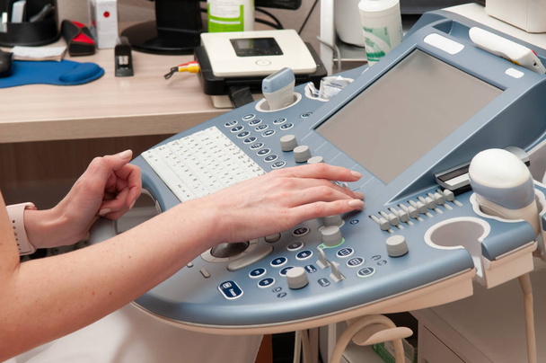Las manos del médico se cierran en la máquina de ultrasonido
 - Foto, imagen