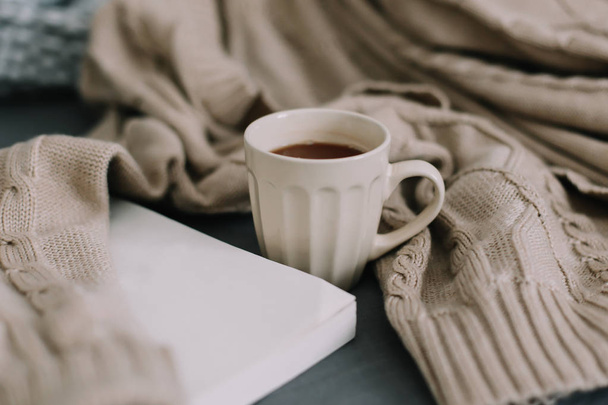 Wool beige sweater, warm knitted plaid, a book and coffee cup. Breakfast in bed. Sweet home. flat lay, still life - Fotó, kép