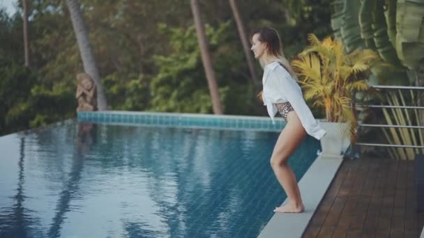 Beautiful young woman with sexy body in swimsuit jumping in to a pool - Metraje, vídeo