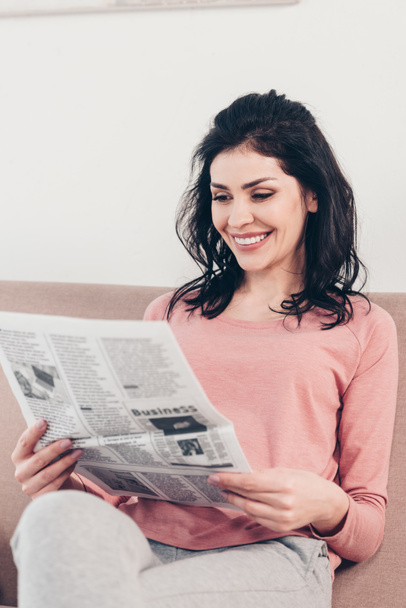 自宅で座って新聞を読んで美しい笑顔の女性 - 写真・画像