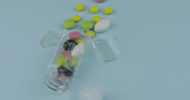 Törött üveg jar sok különböző tabletták és kábítószer spinning a kék háttér - Felvétel, videó