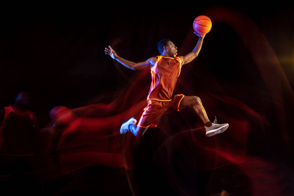 Young basketball player against dark background - Foto, Imagen