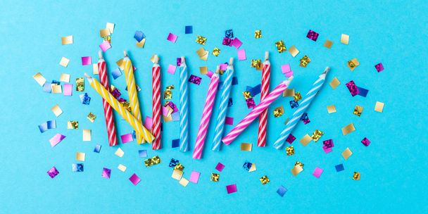 Colorful celebration background with various party confetti and candle decoration. Minimal birthday concept. Flat lay. - Фото, изображение