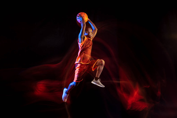 Young basketball player against dark background - Foto, Imagen