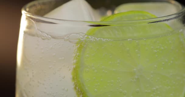 Close-up de uma bebida refrescante refrigerante com bolhas interagindo com gelo e limão
 - Filmagem, Vídeo