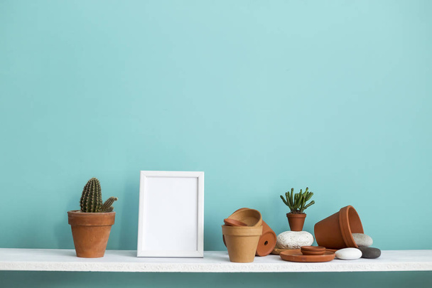 White shelf against pastel turquoise wall with pottery and succulent plant with potted cactus. - Photo, Image