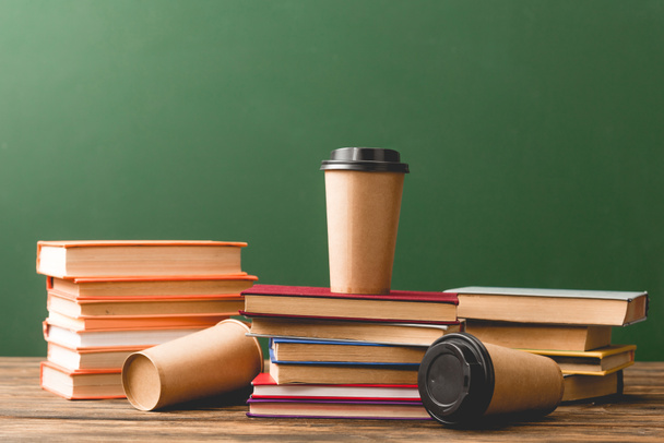 Books and disposable cups on wooden surface on green - Photo, Image