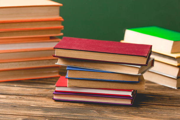 барвисті книги твердого покриття на дерев'яній поверхні ізольовані на зеленому
 - Фото, зображення