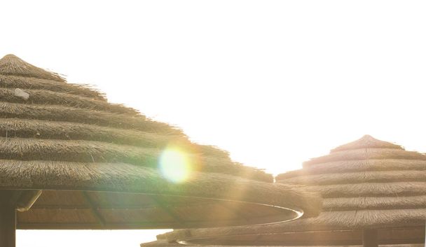 paraguas abstracto de paja sin foco en la playa de mar i sol resplandece panorama de luz escorzo con cielo blanco sobreexpuesto, imagen concepto de vacaciones de verano con espacio de copia vacío para su texto
 - Foto, imagen