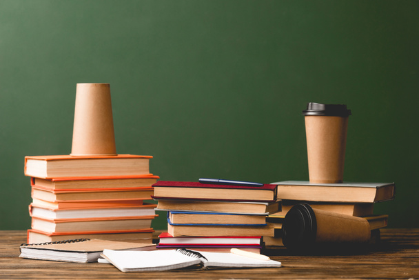 Книги, блокноти та одноразові чашки на дерев'яній поверхні на зеленому
 - Фото, зображення