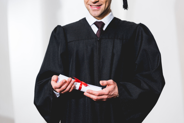 cropped view of happy young man smiling while holding diploma  - Photo, Image