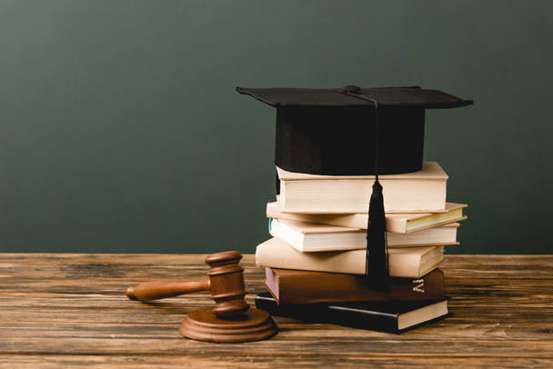 stack of books, academic cap and gavel on wooden surface isolated on grey - Photo, Image