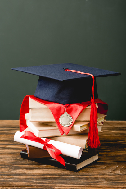 books, academic cap, medal and diploma on wooden surface isolated on grey - Фото, зображення