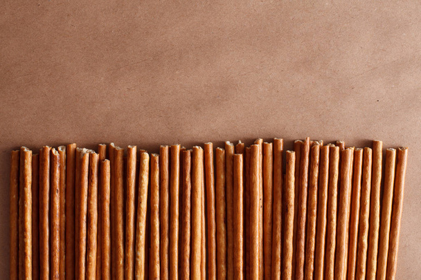 Crispy bread straw on brown paper background - Valokuva, kuva
