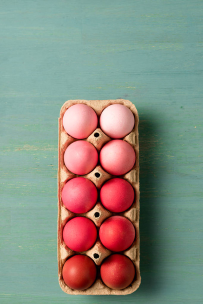 верхний вид окрашенных пасхальных яиц в картонный носитель на текстурированной поверхности
 - Фото, изображение