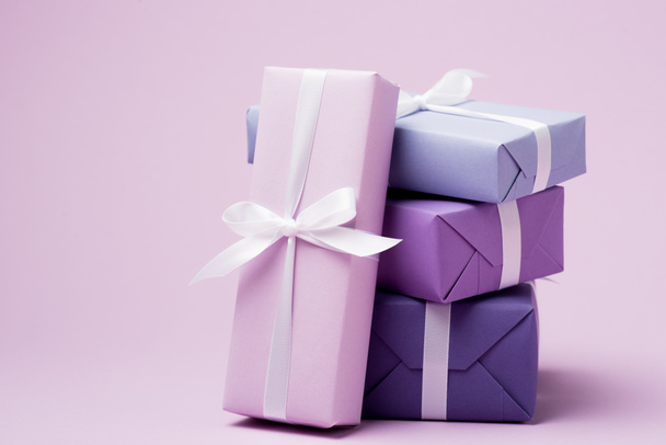 πολύχρωμα κουτιά δώρων με λευκές κορδέλες σε μωβ επιφάνεια - Φωτογραφία, εικόνα