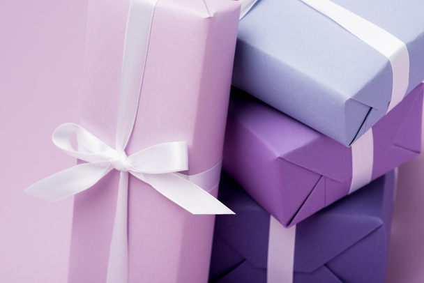 πολύχρωμα κουτιά δώρων με λευκές κορδέλες στο μωβ - Φωτογραφία, εικόνα