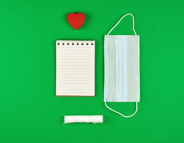 open notebook in line with white sheets, medical mask  - Foto, imagen