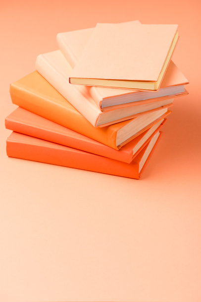 στοίβα από πολύχρωμα βιβλία σκληρό κάλυμμα στην πορτοκαλί επιφάνεια - Φωτογραφία, εικόνα