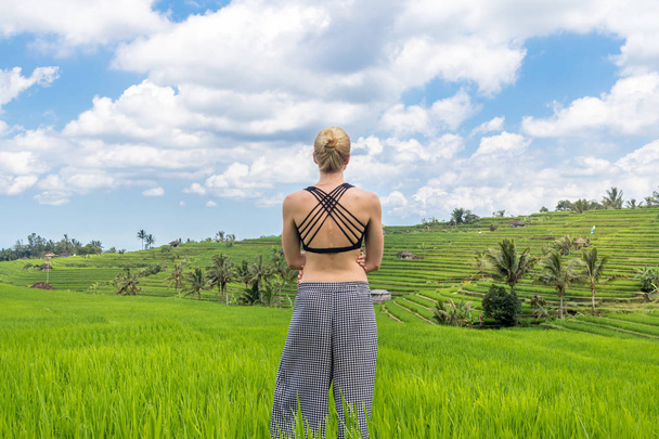 Relajada mujer deportiva casual disfrutando de la naturaleza pura en hermosos campos de arroz verde en Bali
. - Foto, imagen