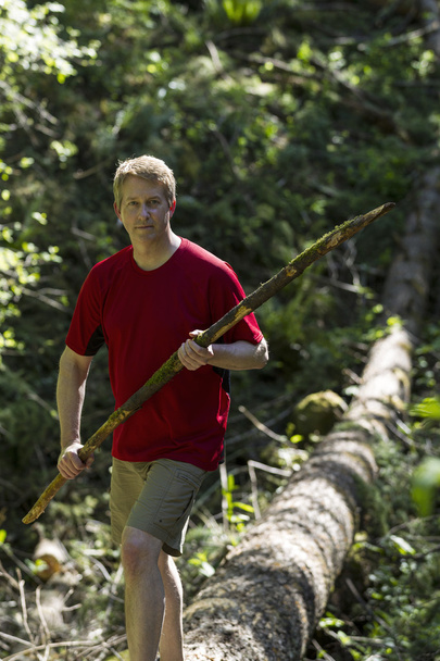 Mature Man hiking over a fallen tree within the woods - Photo, image