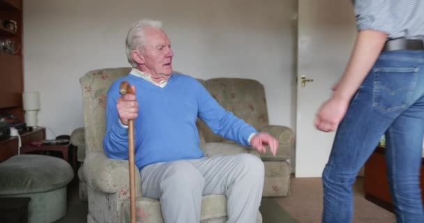 Teenage boy is helping his grandfather out of his armchair. - Filmagem, Vídeo