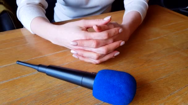 ręce kobiece trzymając mikrofon nad stołem podczas wywiadu - Materiał filmowy, wideo