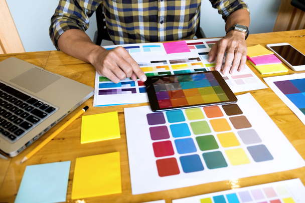 グラフィックデザイナーは、色から色を選択するためにタブレットを使用しています - 写真・画像