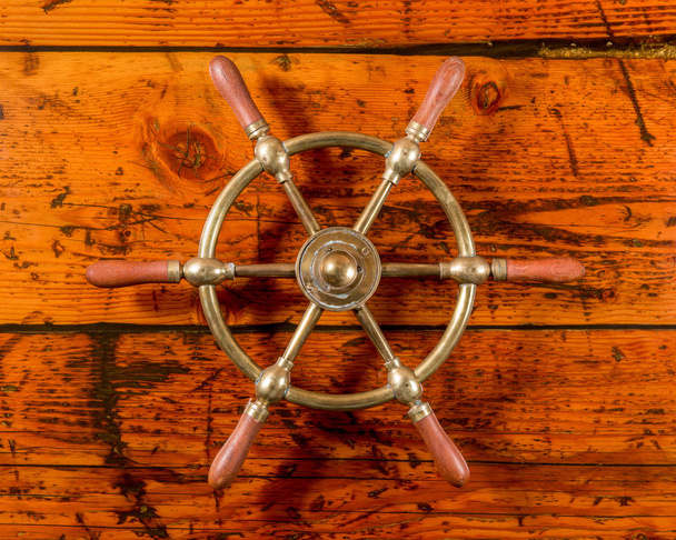 Schiffsrad aus Messing auf strukturiertem Holz - Foto, Bild