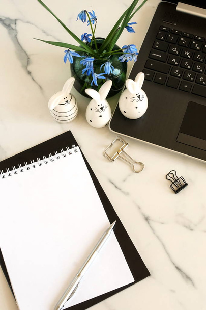 Easter concept banner. Flat lay office table, workspace with laptop, Easter bunny, bouquet blue spring flowers, notebook on marble background. - Foto, Bild