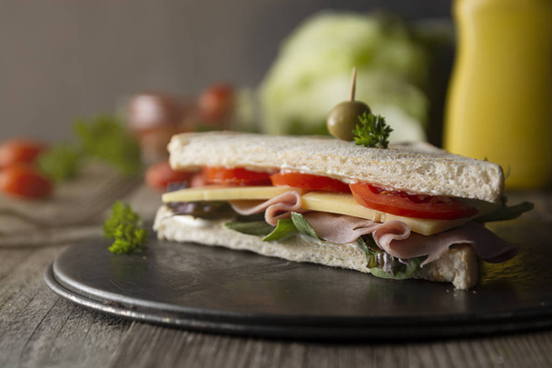 Homemade club sandwich. Toasted white bread triangles with ham, cheese fresh vegetables. Wooden table. - Φωτογραφία, εικόνα
