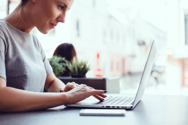 junges schönes Mädchen benutzt einen Laptop im Café, surft im Internet - Foto, Bild