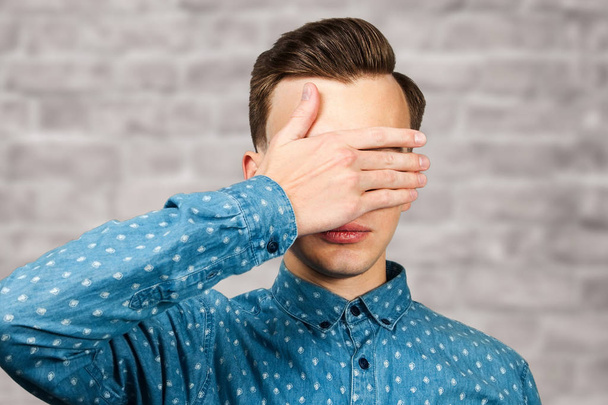 portrait White young man dressed in blue shirt, closes eyes his hands. Man on brick wall background - Fotoğraf, Görsel