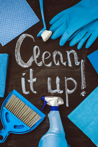 A chamada para "limpar tudo! "escrito em giz em um quadro-negro, cercado por ferramentas de limpeza na casa
. - Foto, Imagem