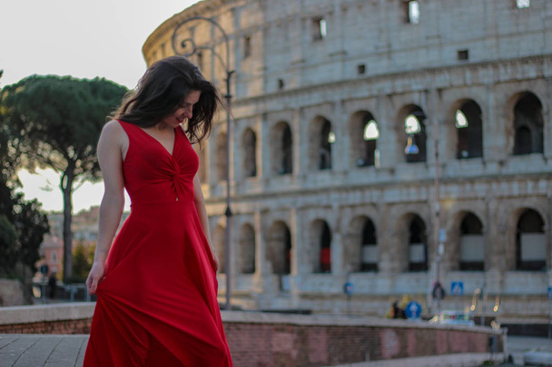 Pretty young girl in red dress in front of Colosseum, Rome, Ital - Zdjęcie, obraz
