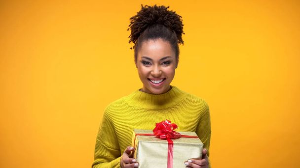 Young woman smiling on camera holding present in hands, holiday celebration - Photo, Image