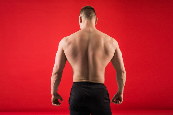 handsome young man in sports athletic form stands on his back against a red background - Foto, immagini