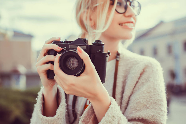 νεαρή ομορφιά γυναίκα παίρνει φωτογραφίες σε vintage κάμερα, γυναίκα φωτογράφος, μοριάρα, ρεπόρτερ του δρόμου - Φωτογραφία, εικόνα