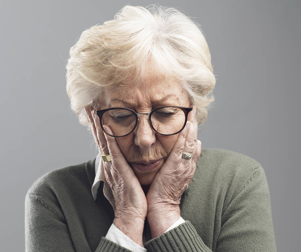 Sad lonely elderly woman posing with head in hands - Фото, изображение