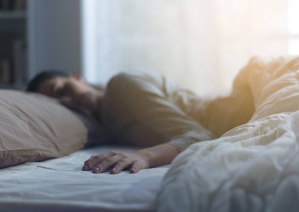 jonge vrouw slapen in haar bed alleen - Foto, afbeelding