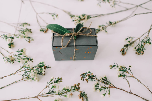 A gift box framed by branches and leaves on white background. Flat lay, top view. Concept of holiday, birthday, Easter, March 8. - Φωτογραφία, εικόνα