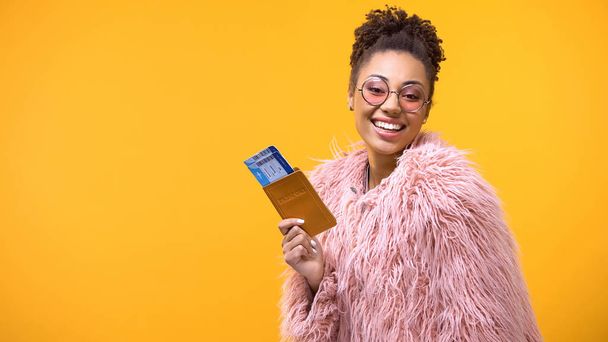 Smiling african woman showing passport and travel tickets on yellow background - Zdjęcie, obraz