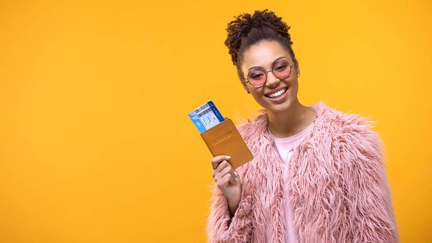 Pretty female holding passport with tickets on bright background, adventure - 写真・画像