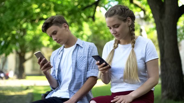 Teenagers using phone instead of interacting, lack of communication, addicted - Foto, afbeelding