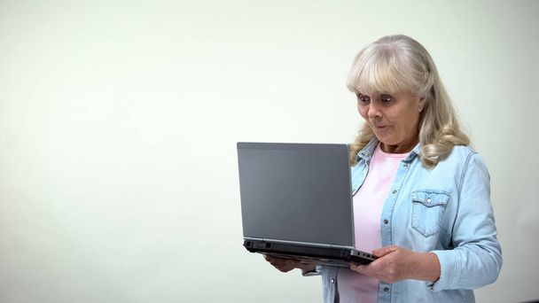 Surprised elderly female reading message on laptop, good news, communication - Foto, imagen