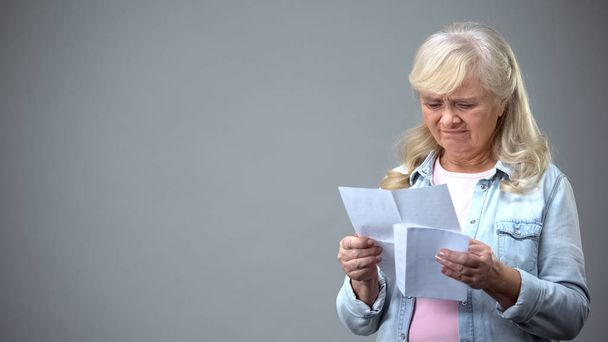 Upset aged female receiving letter from bank, surprised with debt information - Foto, Bild