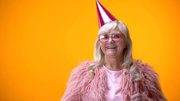 Glamorous old lady in pink coat and party hat celebrating good news, positivity - Фото, зображення