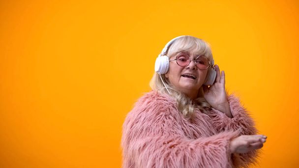 Glamorous old woman in headphones listening music, pretending to be DJ, hobby - Foto, afbeelding
